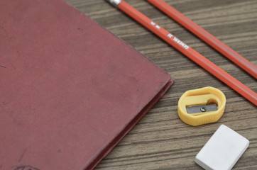 pencil eraser sharpener and notebook on wood sheet close up