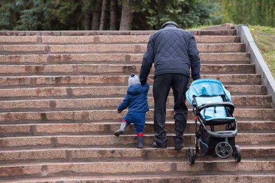 Grandfather With Grandson Holding Hands Walking And Climbing The Stairs