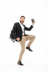 Full length portrait of a joyful excited man holding passport
