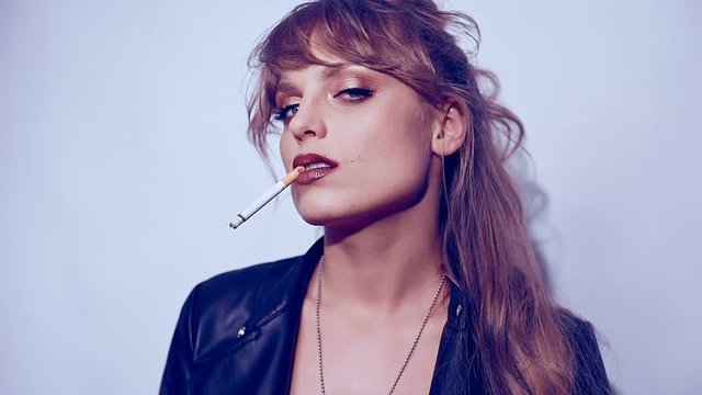 Portrait of elegant blonde woman smoking a cigarette on colorful background in studio
