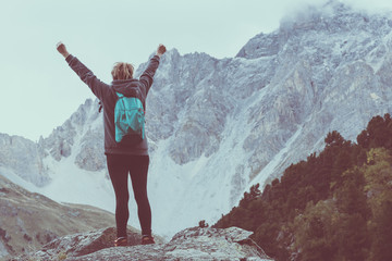 Obraz premium Back view of woman with arms raised in the mountains