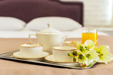 Two white mugs on a tray white bed, breakfast concept