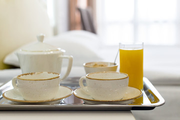 Two white mugs on a tray white bed, breakfast concept