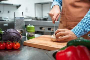 The chef in brown apron cooking in a restaurant kitchen