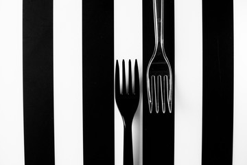 Two forks on black and white stripes background. Flat lay.