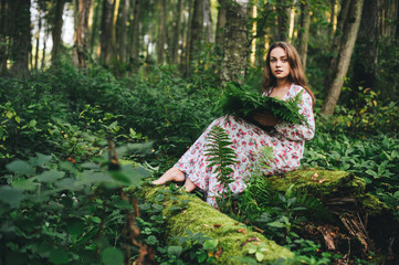 Beautiful girl in a dress in the forest among the fern.