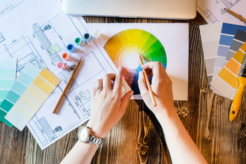 Flatlay interior design with laptop and colour circle diagram, plans and art tools