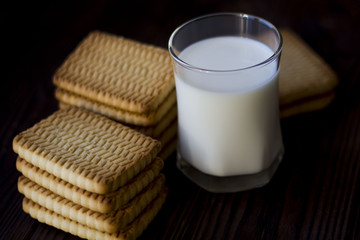 cookies and glasses of milk on a dark wooden table