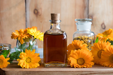 A bottle of calendula tincture with fresh calendula flowers
