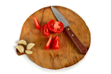 Tomatoes, garlic on an old cutting wooden board. Knife.
