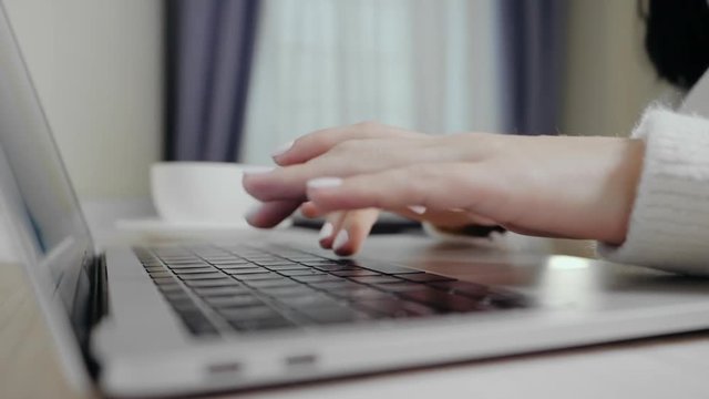 Closeup of business woman typing on laptop. Female hands busy typing on keyboard. Freelancer girl working at home in winter.