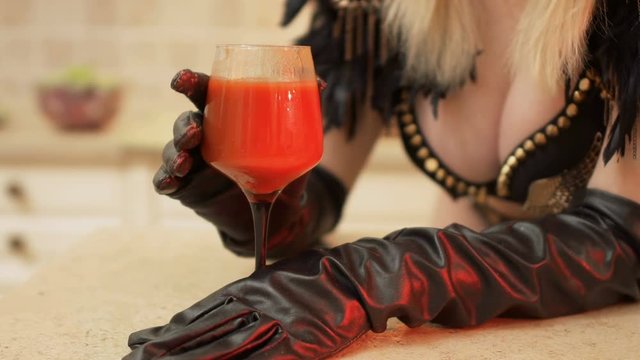 Sexy girl with boobs touches the wineglass with tomato juice