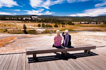 Two women sitting on a bench in the yellowstone national park - obrazy, fototapety, plakaty