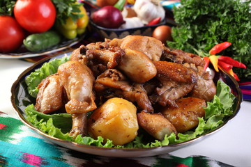 Chicken kebab in a frying pan with potatoes and spices. Serve on a platter with herbs and pepper.Uzbek cuisine.