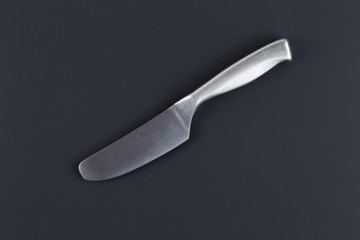 A special kitchen knife for cheese on a dark surface with a soft shadow.