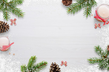 Fototapeta na wymiar Flat Christmas background scene with fir branches, bows, candles, pinecones and snowflakes Free space for copy text on white board. Top view.