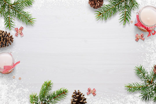 Flat Christmas background scene with fir branches, bows, candles, pinecones and snowflakes Free space for copy text on white board. Top view.