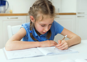 Naklejka na ściany i meble Little girl doing her homework at home.