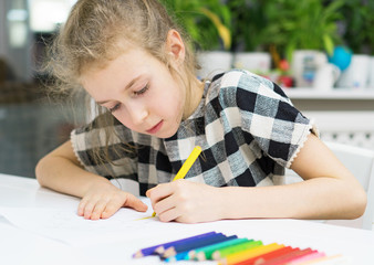 Little girl drawing with pencil at home.