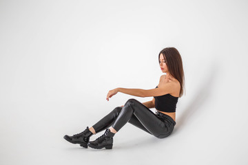 Fototapeta premium Beautiful girl brunette posing in black pants and top on a white background