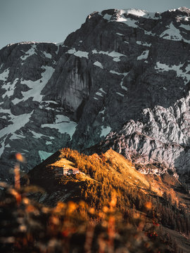 Alm auf dem Gipfel eines Berges angestrahlt vom Abendrot im Vordergrund eines h&ouml;heren Berges