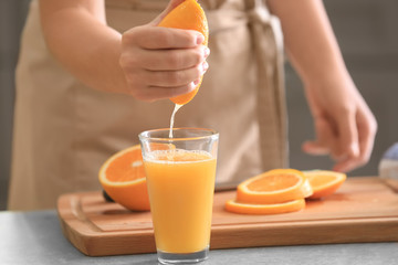 Woman squeezing juice from ripe orange in kitchen