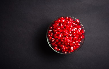 Pomegranate fruits in a bowl on black background