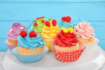 Stand with beautiful cupcakes on blurred background, closeup
