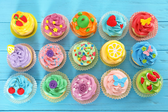 Beautiful cupcakes on color wooden background, top view