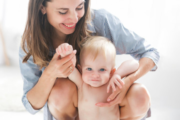 Mother with baby at home. Happy family with newborn playing indoors