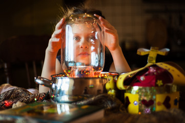 A girl makes an experiment with a jar, pots and a garland
