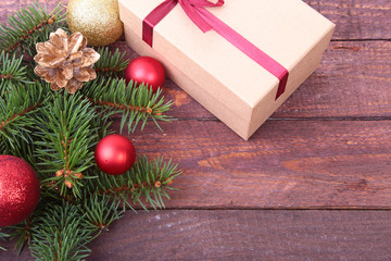 Christmas fir tree with gift box and balls on wooden board