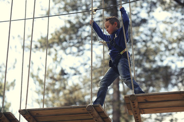 boy walking across high ropes