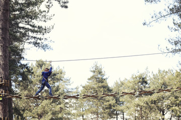 child crossing high rope bridge
