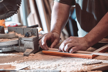 The carpenter in the workshop makes frames for paintings.