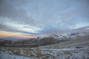 Зимний закат над снежными горами, красивые цвета на облачном небе, заход солнца, природа Северного Кавказа