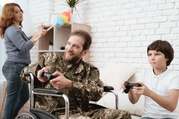 The veteran in a wheelchair came back from the army. A man in uniform in a wheelchair with his family.