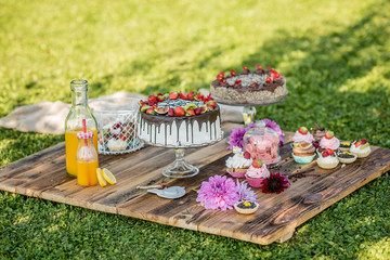 selection of sweet cakes in a garden picnic birthday celebration  - 182905874