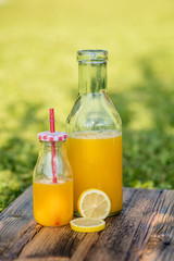 freshly sqeezed orange juice in a glass bottle outdoor shot in a garden