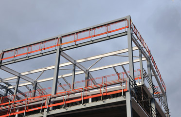 steel frame building under construction with orange safety railings and girders