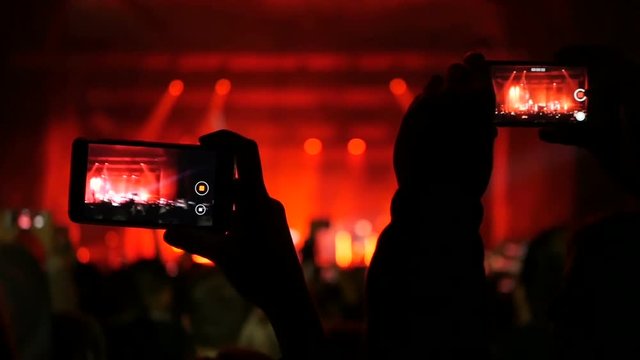 People taking photos or recording video with their smart phones at music concert