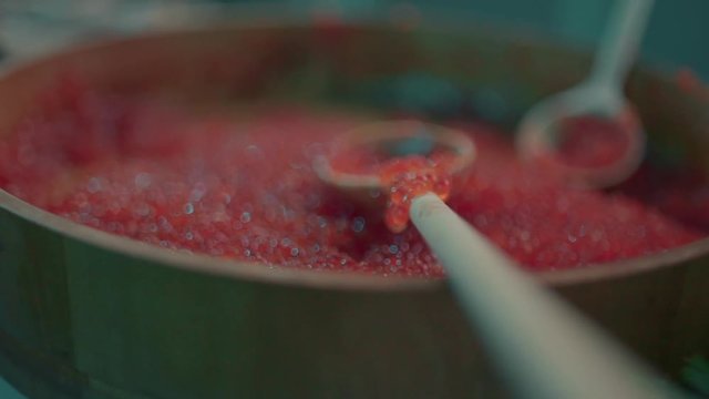 Red caviar dripping from a traditional wooden spoon. Macro food in slow motion,
