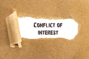 The text Conflict of interest appearing behind torn brown paper