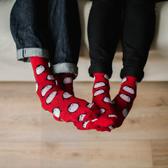 Feet in woollen socks. Pair relaxing with a cup of hot drink and warming up their feet in woollen socks. - 182909254
