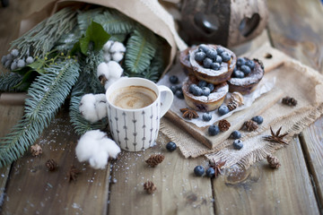 muffins with blueberries on a wooden background, bouquet of branches and coffee in a white mug