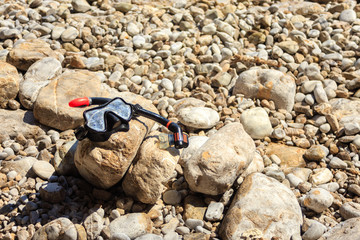 mask and snorkel set on a rocky beach