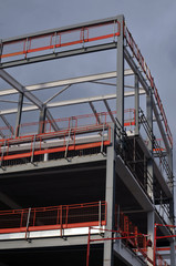 Naklejka premium steel frame and roof of a building under construction with orange safety railings and girders