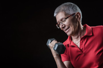 Champion senior lady, lifting weights using dumbbells and feeling strong and powerful; dramatic...