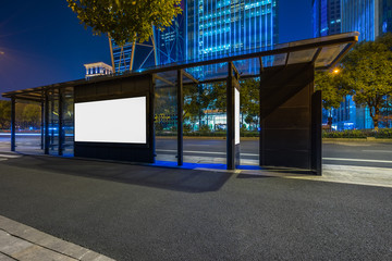 Blank billboard on bus stop at night.