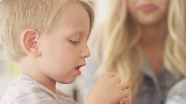 Young loving mother gives her son a curly frie piece. 